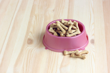Fototapeta na wymiar dog food, bone-shaped biscuits in a pink plastic bowl, top view.