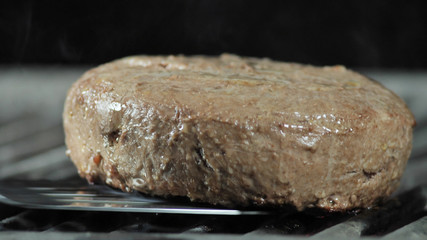 A large meat patty is grilled for a burger