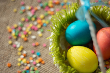 Multicolored eggs in easter festive basket on canvas napkin.