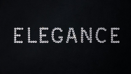 Word Elegance made of shiny white swarovski crystals placed on black leather