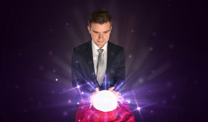 Young businessman sitting with crystal ball in action