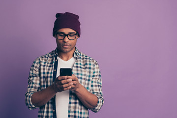 Photo portrait of concentrated cool guy user using smart phone holding in hands device texting letter  reading getting sms isolated violet background copyspace