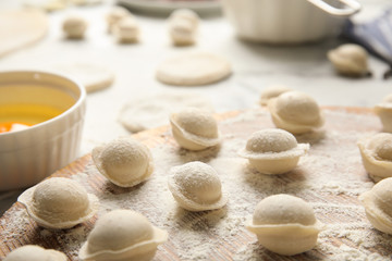 Fototapeta na wymiar Raw dumplings on wooden board, closeup. Process of cooking