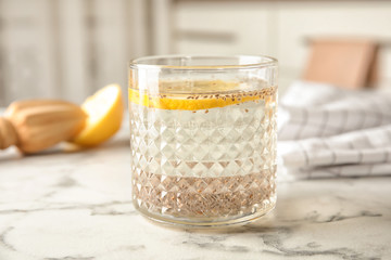 Glass of water with chia seeds on table against blurred background