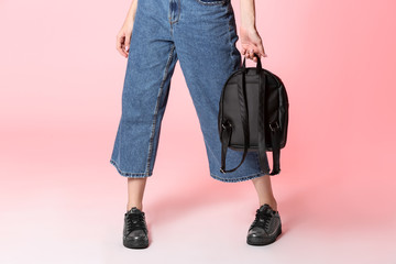 Naklejka premium Fashionable woman in stylish shoes with backpack on color background