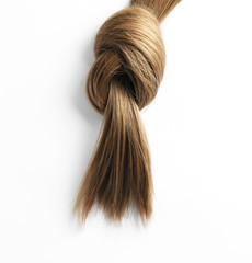 Beautiful strand of brown hair tied in knot on white background, top view. Hairdresser service