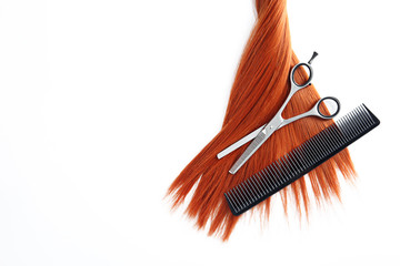 Beautiful strand of straight red hair, scissors and comb on white background, top view. Hairdresser...