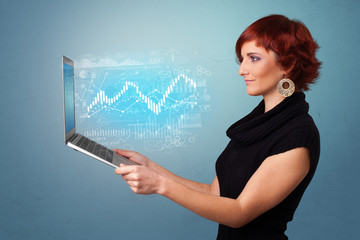 Woman holding laptop projecting financial information, diagrams and charts 
