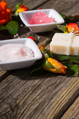 beauty product samples with rose flowers and buds on weathered old wooden table