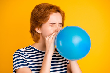 Close-up portrait of nice charming attractive girlish childish lady blowing blue baloon festal event celebratory day preparation tradition isolated over bright vivid shine yellow background