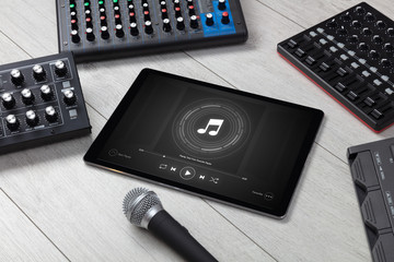 Playing song on tablet with electronic music instruments around
