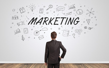 Young manager in doubt looking to a wall with business concept
