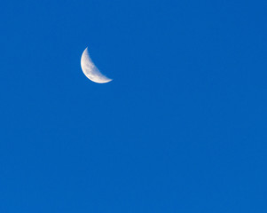 Obraz na płótnie Canvas The moon during the day against a clear blue sky.