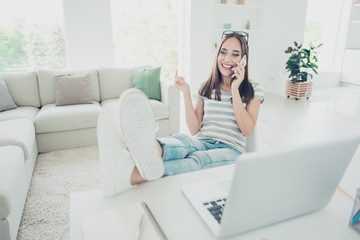 Close up photo beautiful she her lady notebook telephone hand arm tell speak amazed smart phone legs table wear jeans denim striped t-shirt sit comfort chair house bright living room indoors
