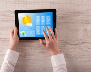 Man hand checking weekly weather forecast on tablet
