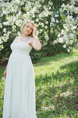 Spring mood, beautiful pregnant woman smell flowering cherry tree, enjoying nature, white floral garden.