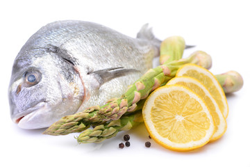 Dorado fish on white background with asparagus and lemon