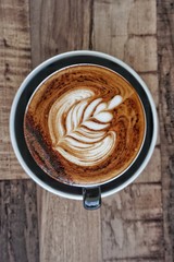 cup of coffee with chocolate dusting on wooden background