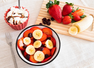 Stay fit with healthy snack, fruit like banana and strawberry and a small cup of cream
