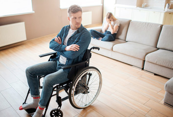 Young man with inclusiveness and disability sit on wheelchair in front. Hands crossed and upset....