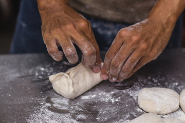 Fototapeta premium Male hands chef close-up, knead the dough, cook the dough on a dark background