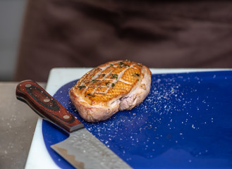 Roast duck breast and knife on blue plastic сutting board