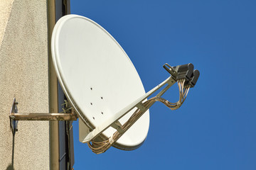 Eine Satellitenschüssel an einer Hauswand.
