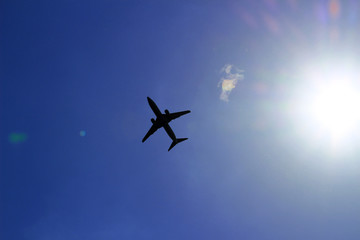Silhouette of a jetliner flying in a blue sky where the sun shines