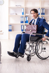 Young male employee in wheelchair working in the office 