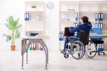 Young male employee in wheelchair working in the office 