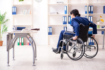 Young male employee in wheelchair working in the office 