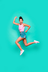 Fototapeta na wymiar Vertical full length body size photo beautiful she her stylish trendy hairdo jump high win winner victory achievement wear casual pink tank-top jeans denim shorts isolated teal turquoise background