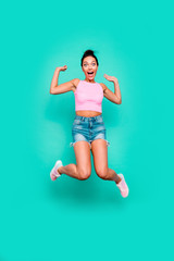 Vertical full length body size photo beautiful she her stylish trendy hairdo jump high unexpected lucky achievement wear casual pink tank-top jeans denim shorts isolated teal turquoise background