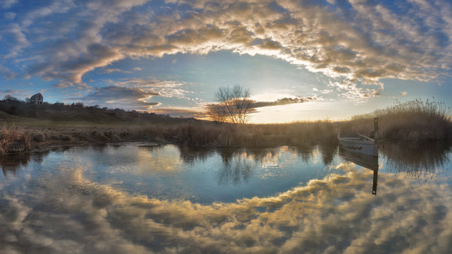 Sunrise on a calm river Southern Buh, Ukraine. In the blue sky clouds. Panoramic view.