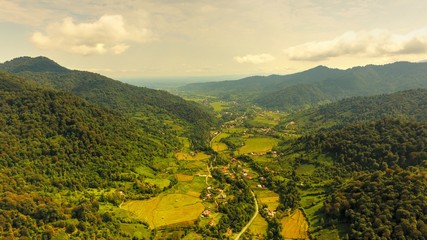 An aerial long shot of a green valley and mounts and villagerian