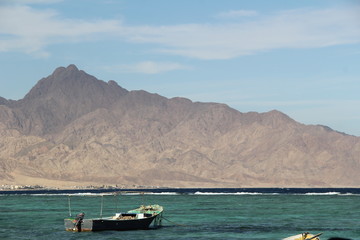fisherman's boat in the sea against the backdrop of mountains and blue sky