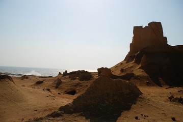 A scene of rocks and hills beside of the ocean