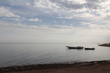 Lone fisherman boat in the sea with mountains on the horizon in a hazy haze