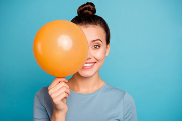 Close up photo of cute attractive lady hold hand orange ballons for anniversary hide feel content enjoy rejoice free time dressed cotton fashionable spring clothes isolated on blue background