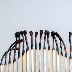 row of wooden matches glows, several embers are smoldering, small flames