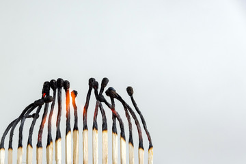 row of wooden matches glows, several embers are smoldering, small flames