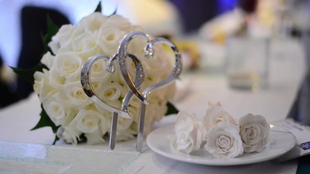 Close up of Silver heart shaped in front of a wedding bouquet lying on the table