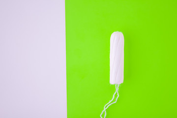 The concept of the menstrual cycle, menstruation and intimate products with an internal swab, on green background with copy space