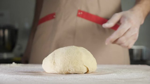 slow motion of chef baker throws the dough on the table, close-up.