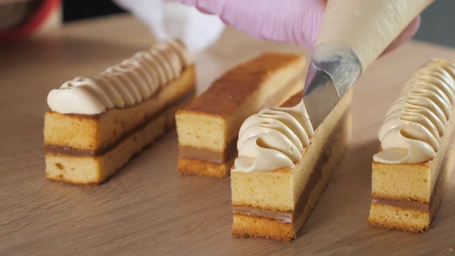 Baker chef decorates biscuit with cream from pastry bag. Hands close-up. selective focus