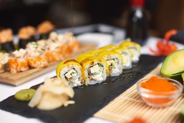 Freshly prepared sushi roll covering by teriyaki sauce and served with wasabi and marinated ginger. Special offer for lunch from three different sources with rice and seafood in Japanese restaurant.