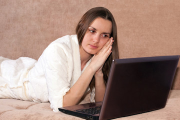 Woman with laptop lies on the sofa