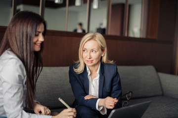 Two caucasian female coworkers working together on business project using laptop, female executive explaining new online idea to coworker at office