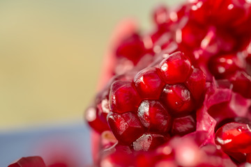A pomegranate with grains of closeup. Beautiful blurry backdrop and red seeds pomegranate. Macro image of fruit. Soft focus. Copy space. Healthy concept.