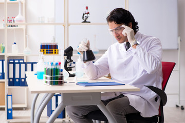 Young handsome chemist working in the lab 